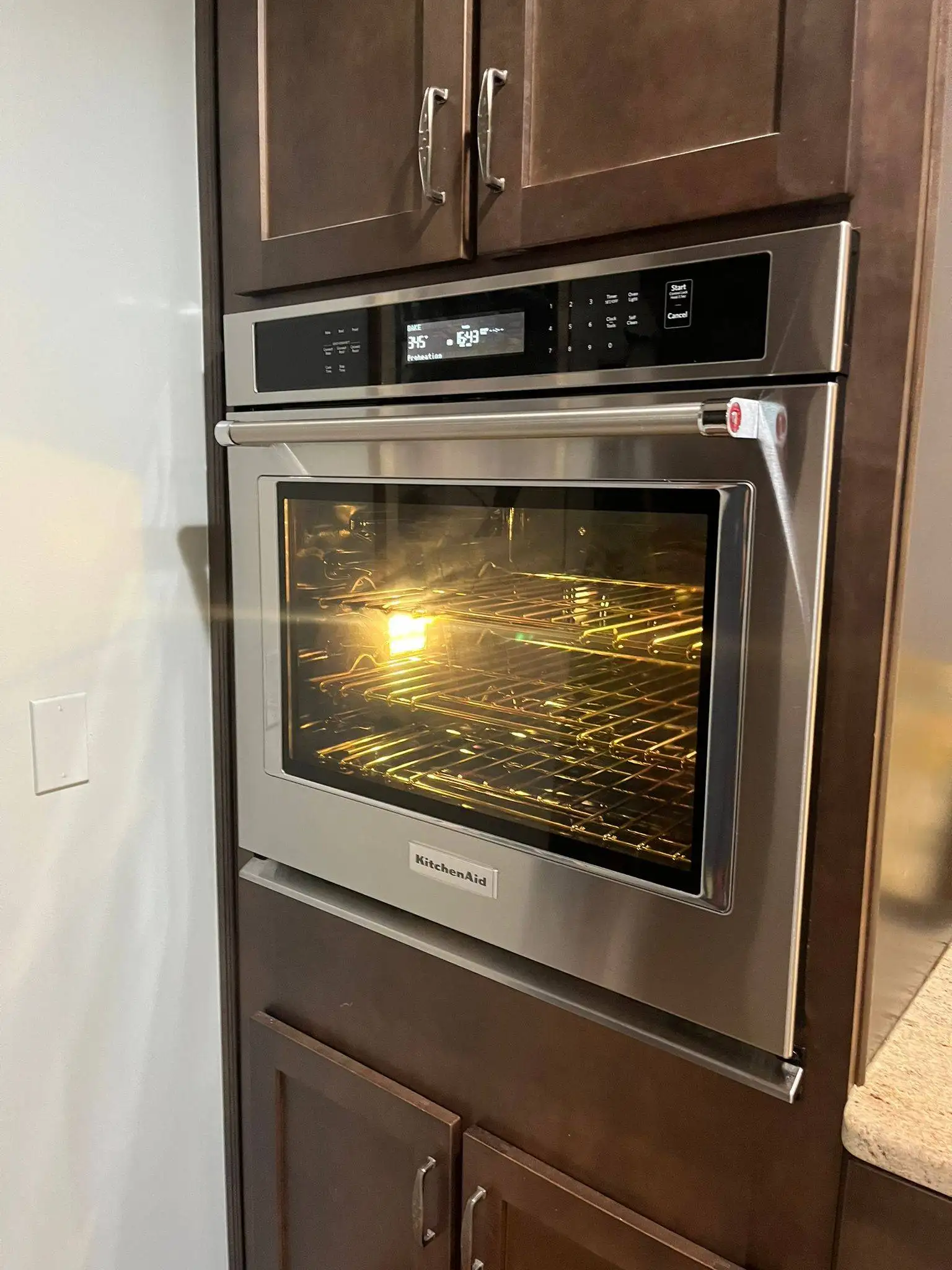 KitchenAid stainless steel wall oven built into dark wood cabinetry