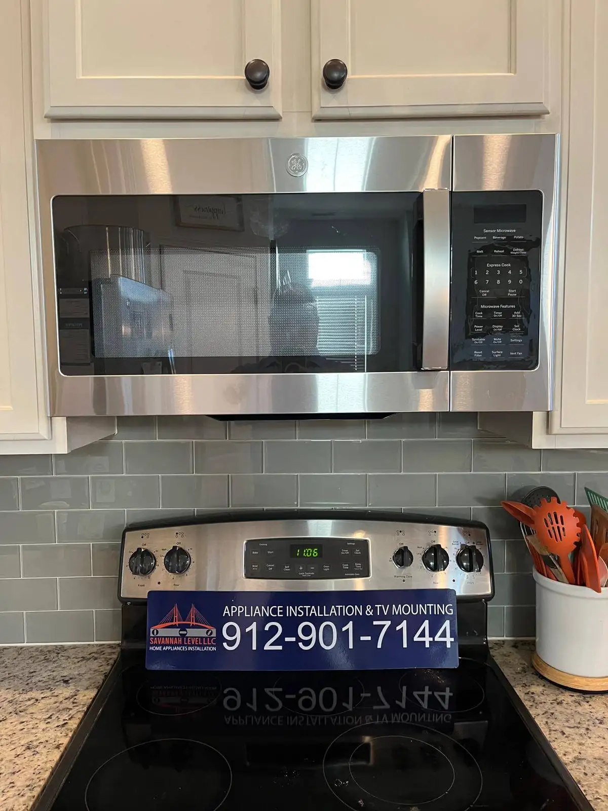 Stainless steel over-the-range microwave installed above a stove with green subway tile