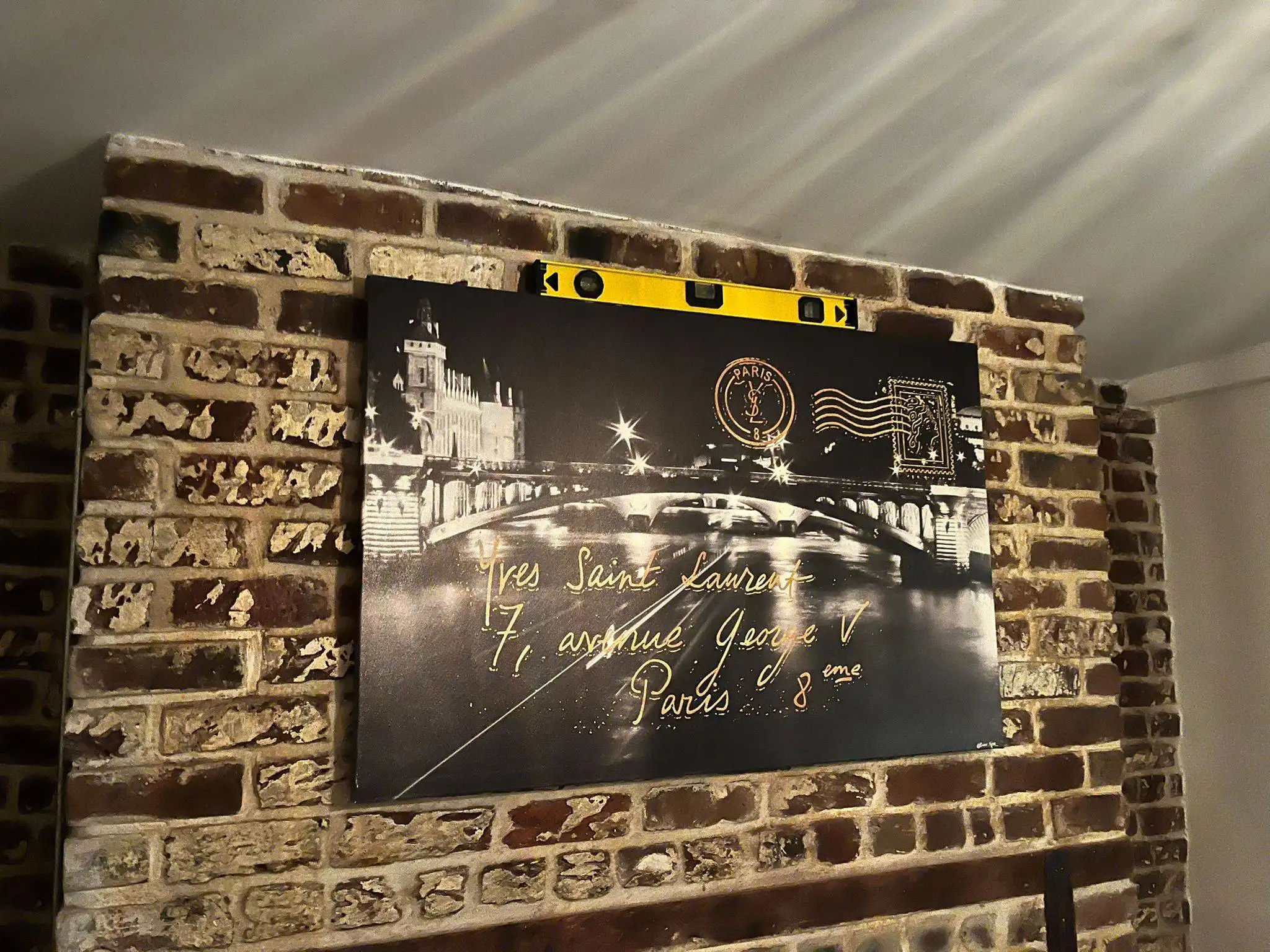 Framed Paris canvas artwork mounted level on an exposed brick wall