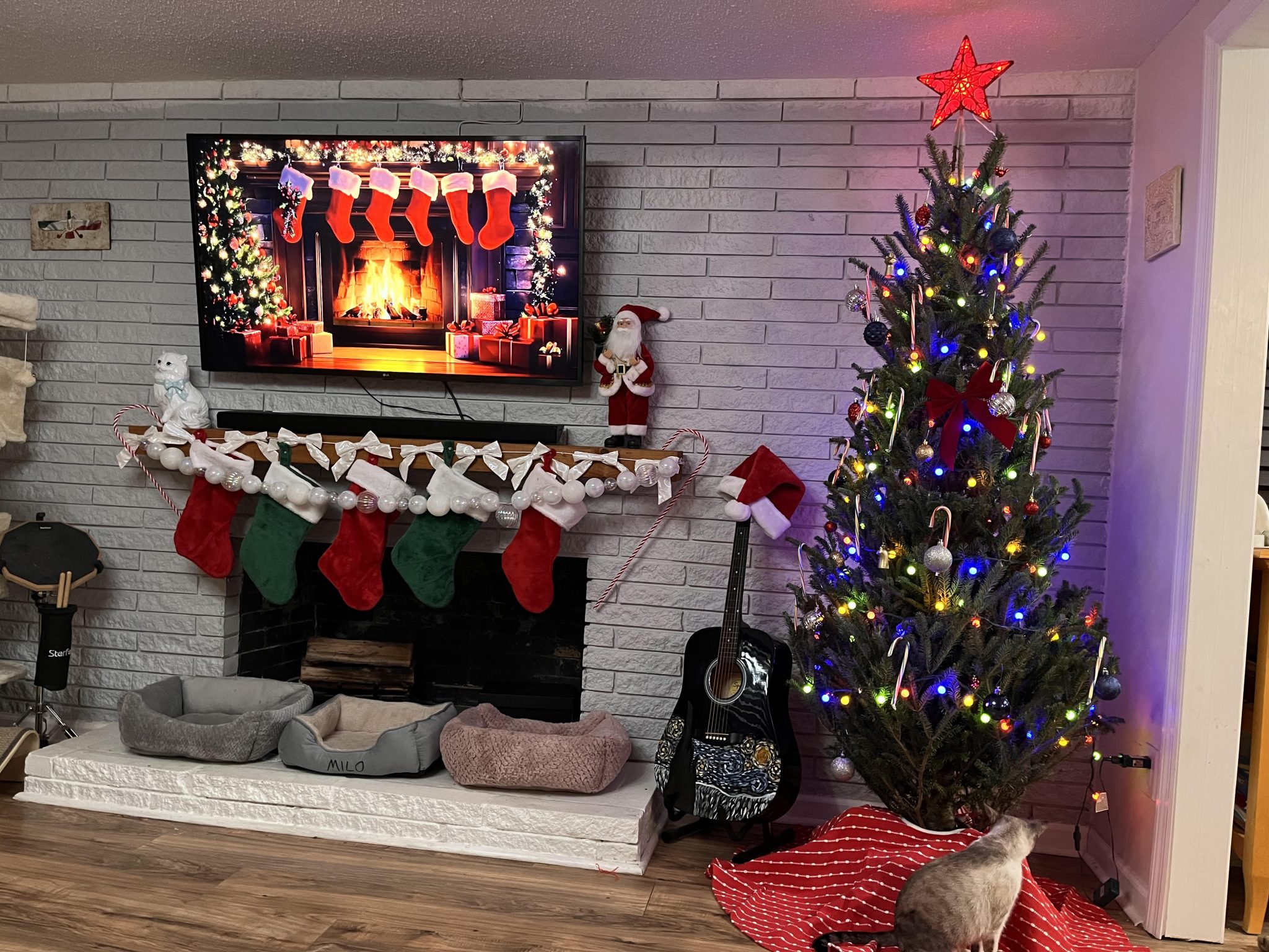 TV mounted above a white brick fireplace decorated for the holidays