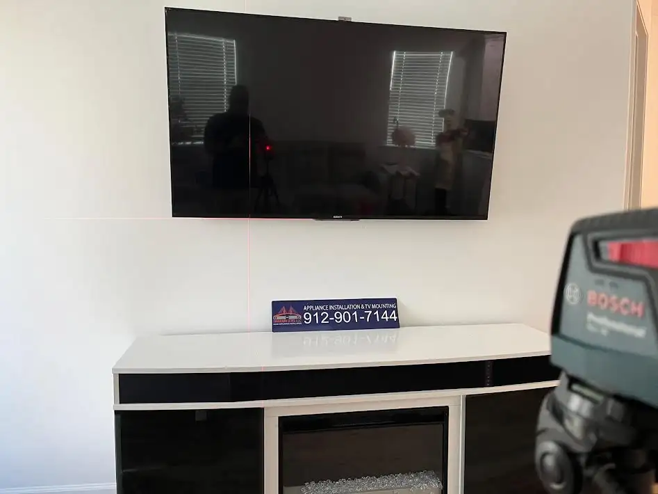 A wall-mounted TV with a black and white table underneath it.
